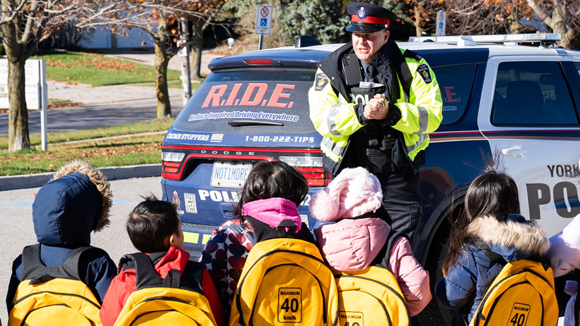 A man in a police uniform stands in front of a group of children
