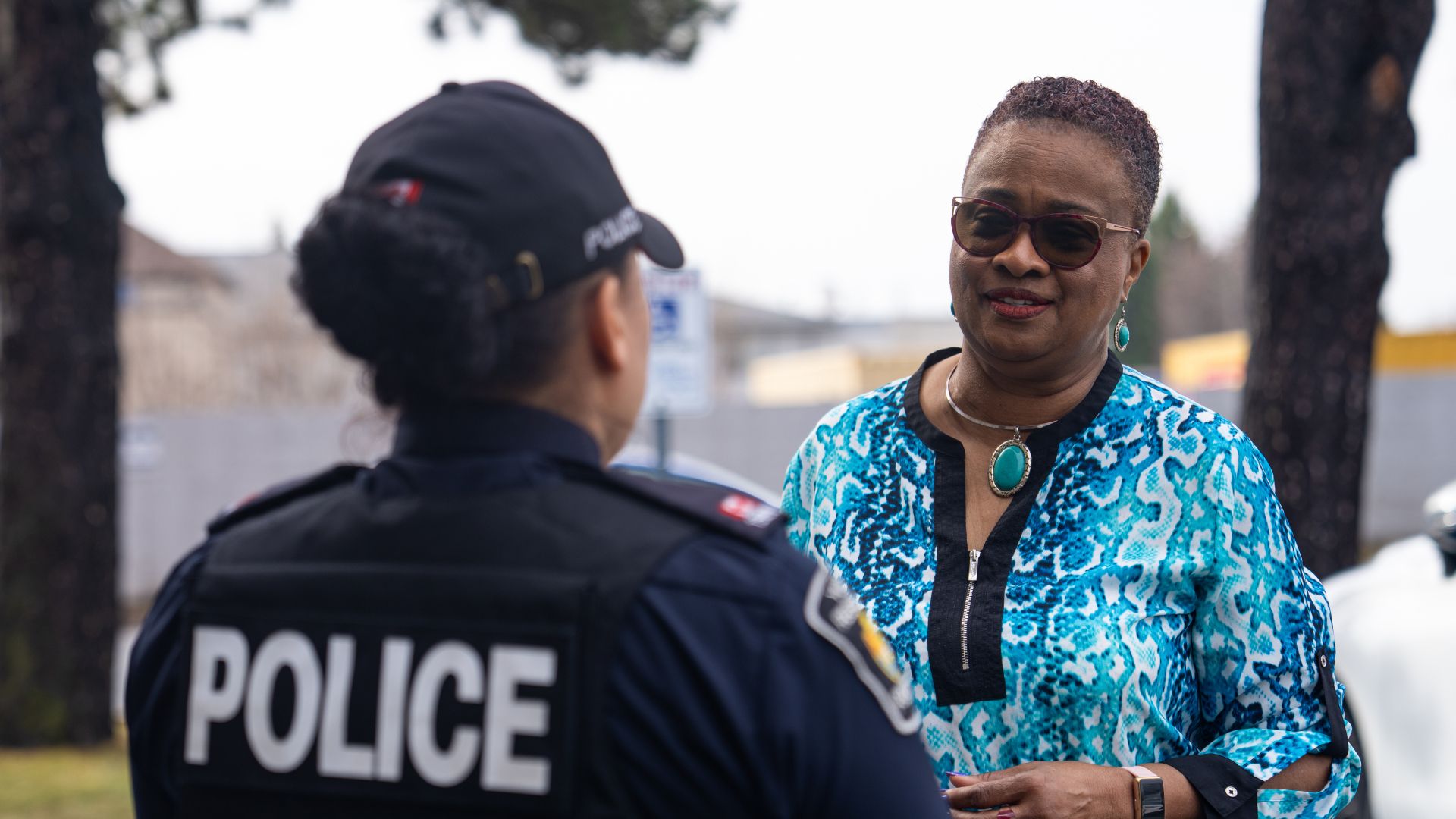 A woman speaks to another woman in a police uniform