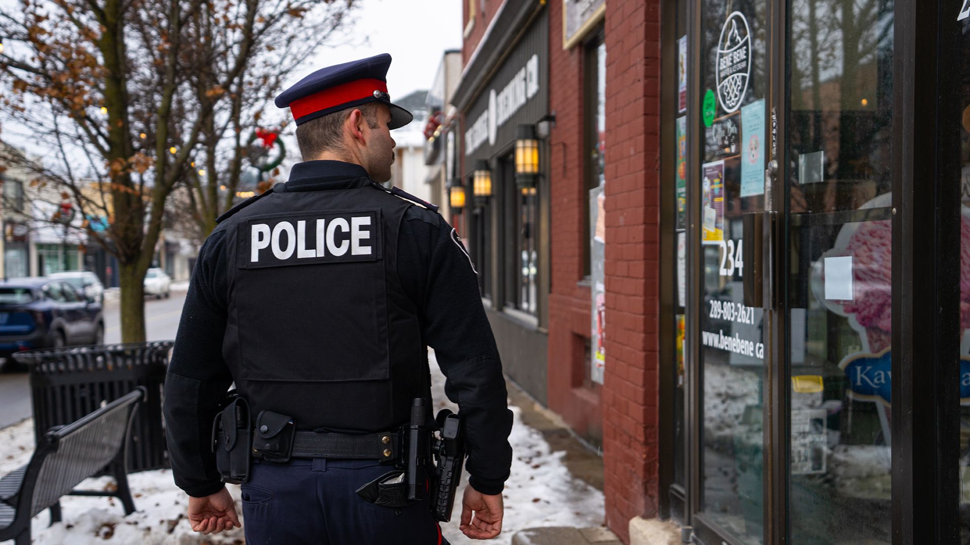 An officer walks past a business on a snowy day