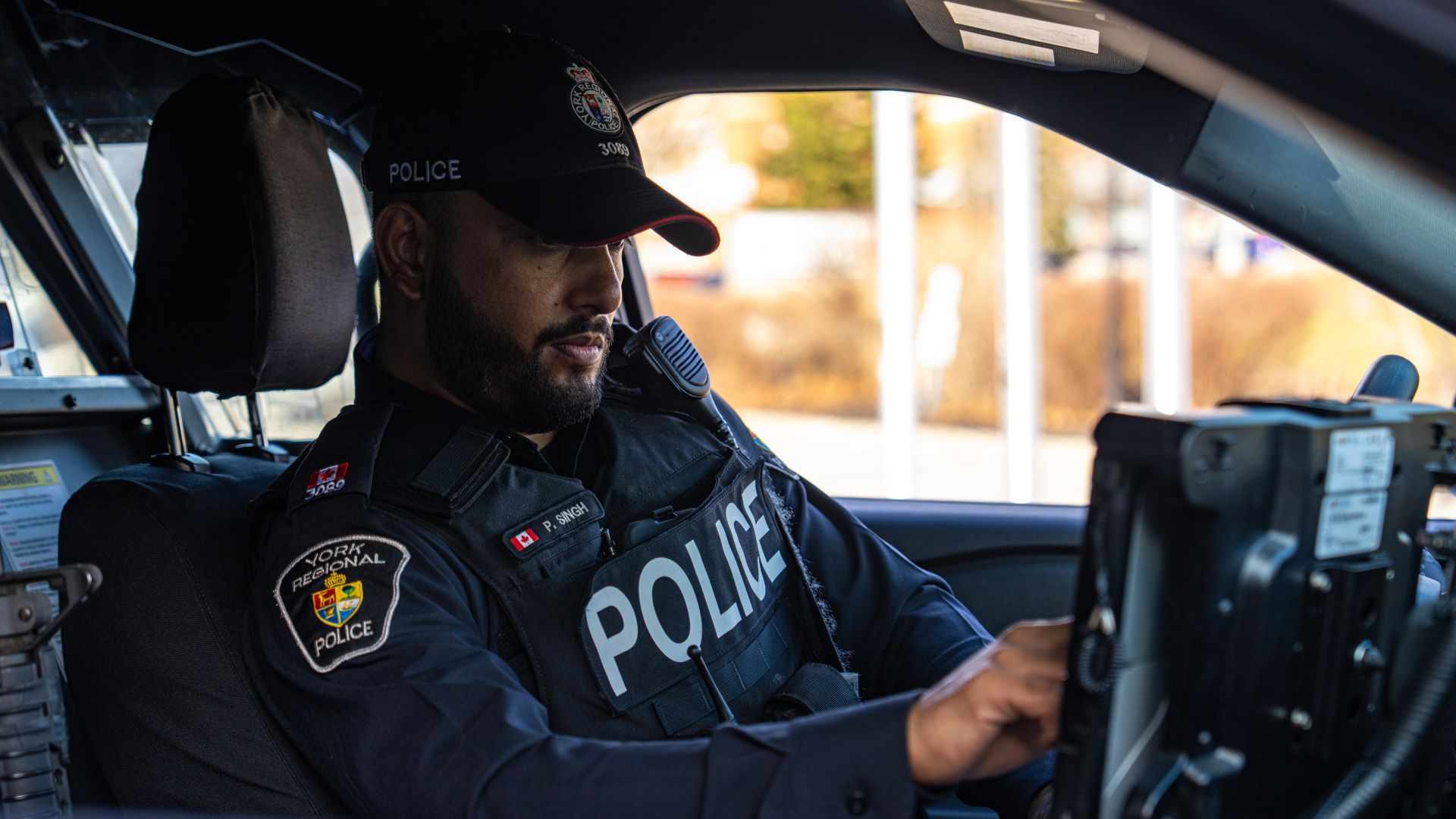 Police officer using in-cruiser laptop while parked.