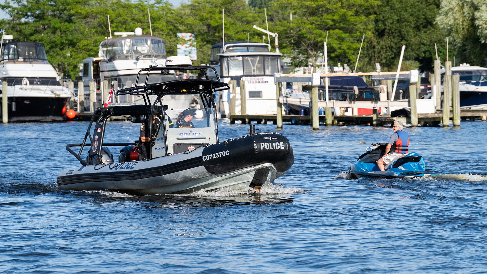 A York Regional Police boat passes a man on a seadoo