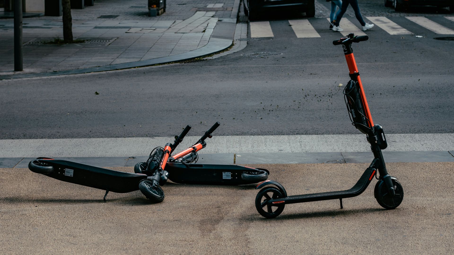 A photo shows three e-scooters on the side of a road.