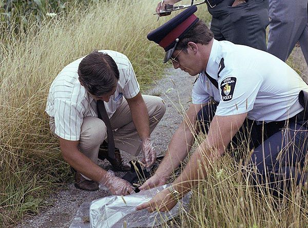 Investigators sort cold case victim, Kathleen McLaughlin's personal affects at the crime scene.