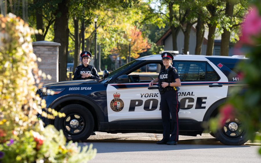 Two officers with a police cruiser in a park.