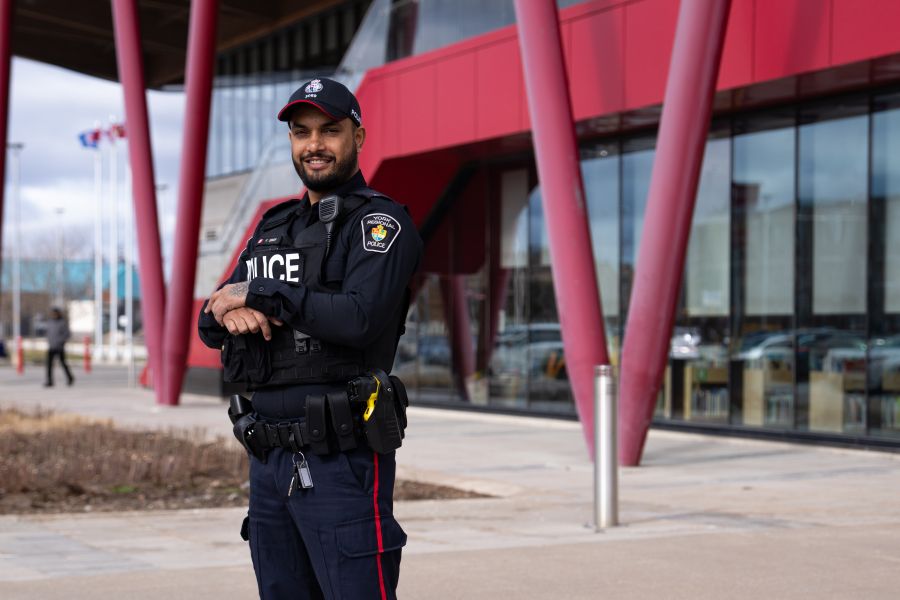 Police officer smiling and standing in front of a community center.