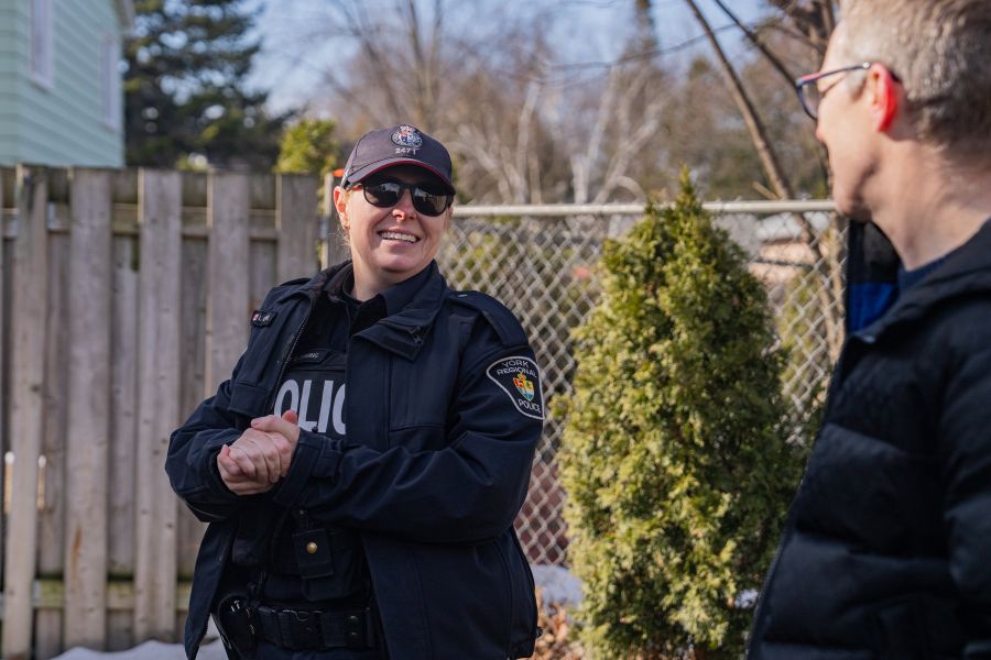 Police officer chatting with civilian in a backyard.