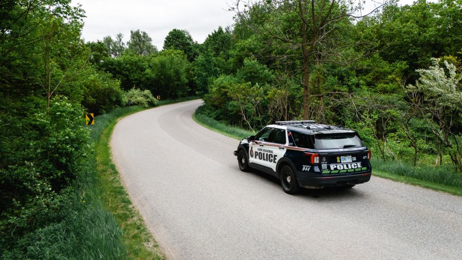 York Regional Police cruiser driving away on a path with a lot of green foliage.