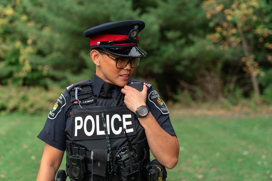 Police officer speaks into a radio at a park.