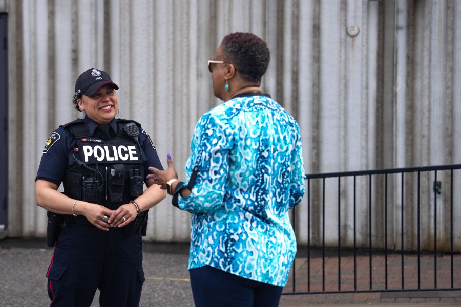 Police officer chats with a civilian woman outdoors.