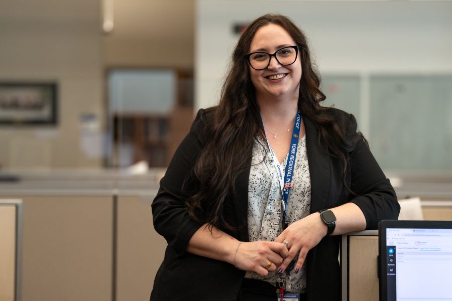 York Regional Police employee leaning against a cubicle and smiling.