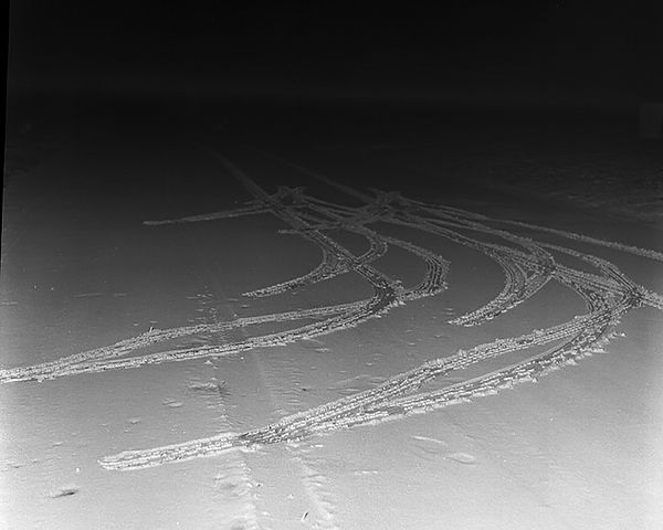 Crime scene photo of curving tire tracks in the snow.