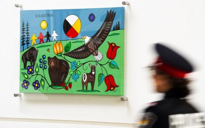 A person in a police uniform walks past a colourful piece of art