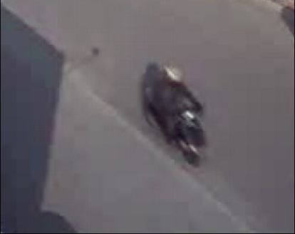 Suspect, wearing dark-coloured clothing, riding a scooter or small motorcycle and wearing a grey helmet with a full-face visor.
