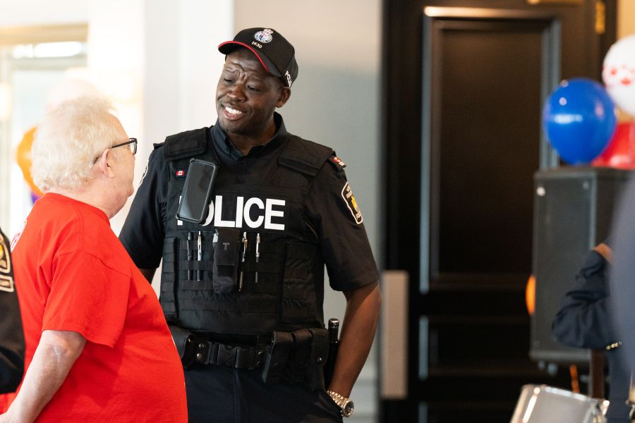 A man in a police uniform speaks to a woman in red