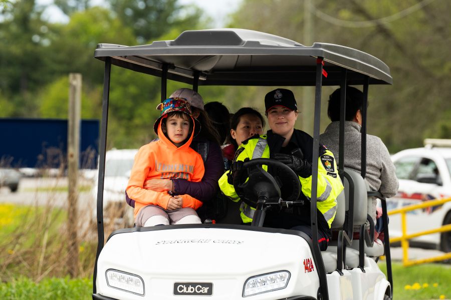 A woman in a police uniform drives a golf cart