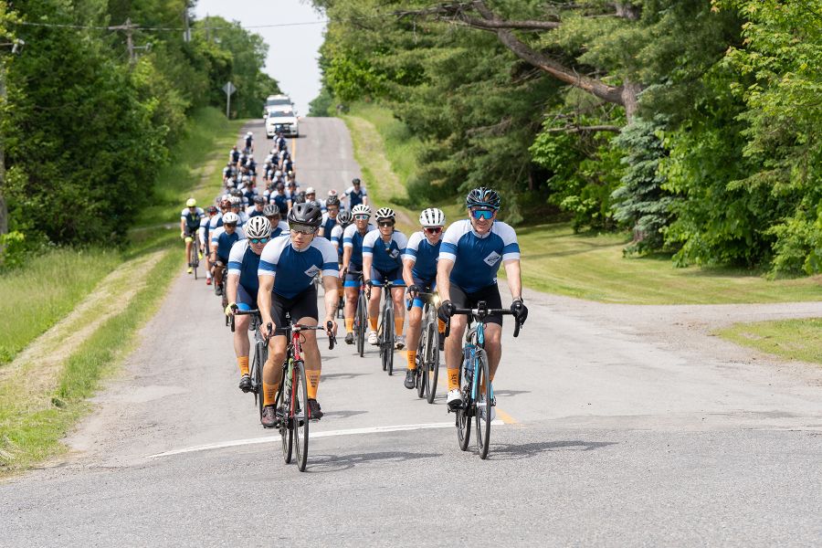 A group of cyclists ride in a line on a closed road