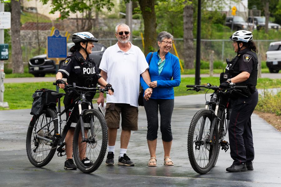 Officers with bicycles speak with two seniors in a park.