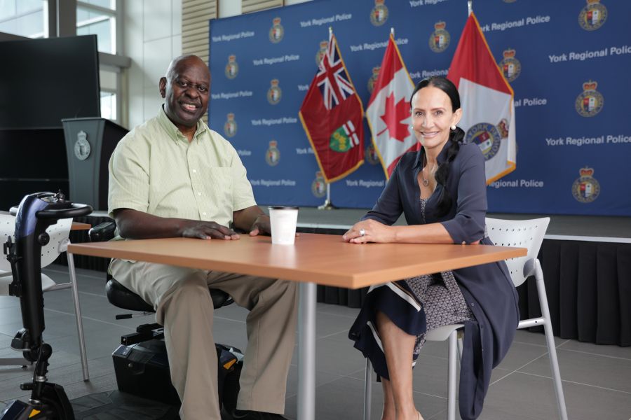 Two people sit at a table, including one with a mobility scooter