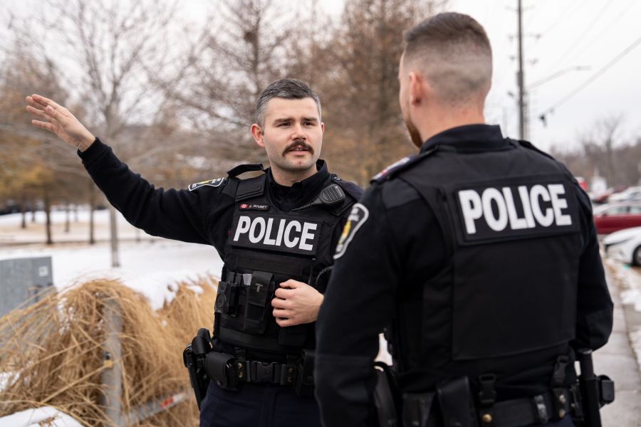 Two police officers talking outdoors, one is pointing in the distance.