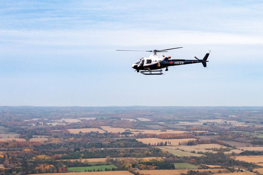 A helicopter flies high above a rural setting