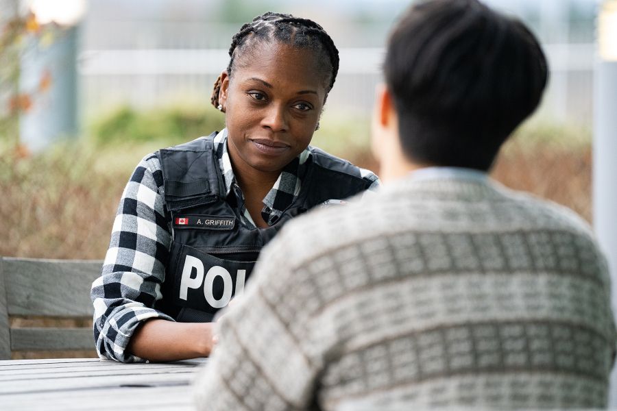 An officer speaks with a man sitting at a table