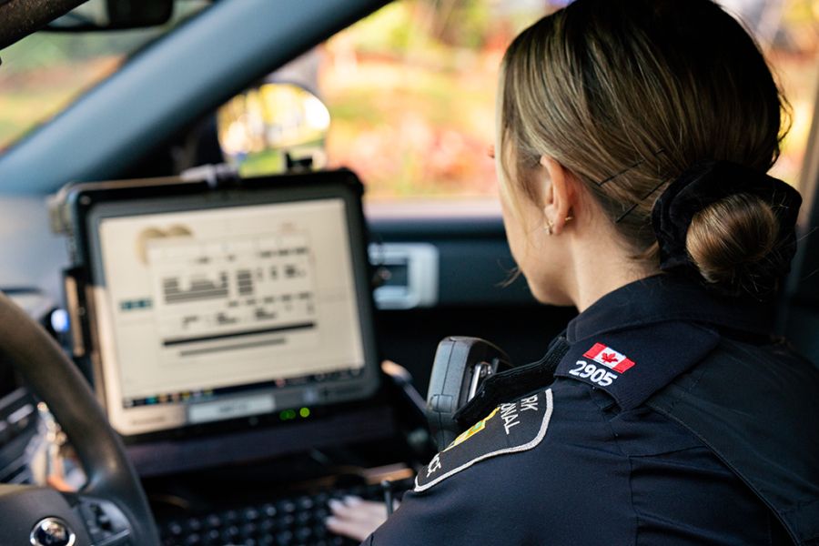 A woman wearing a uniform looks at a laptop