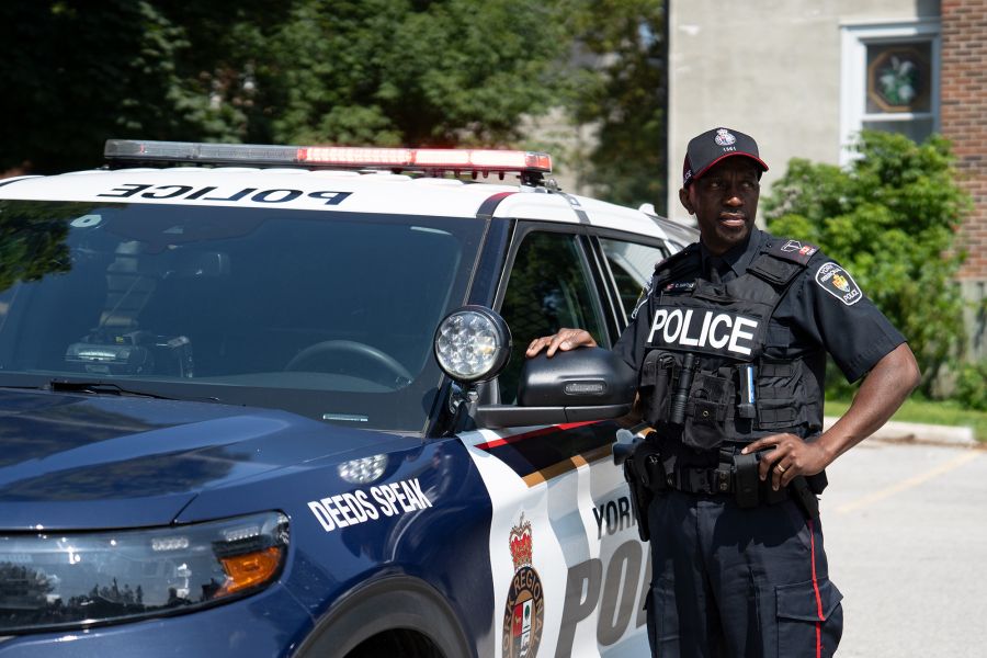 A man in a police uniform next to a police cruiser