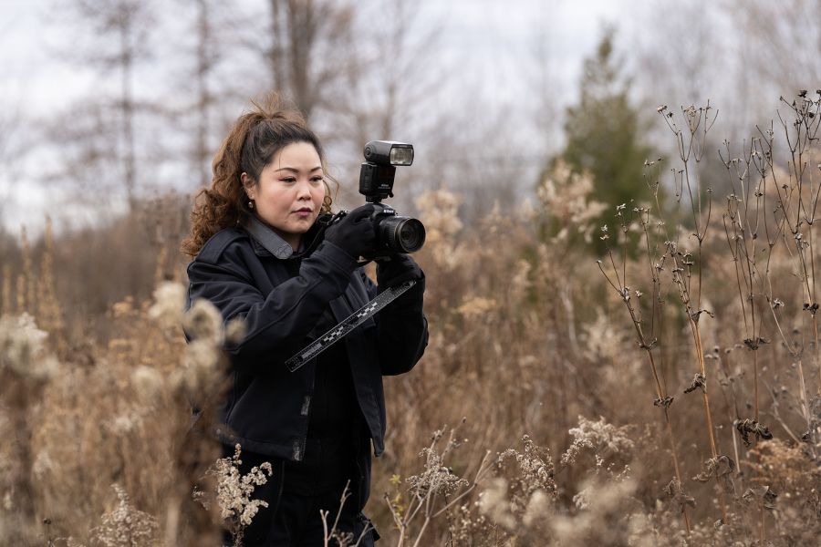 A woman holds a camera in a meadow