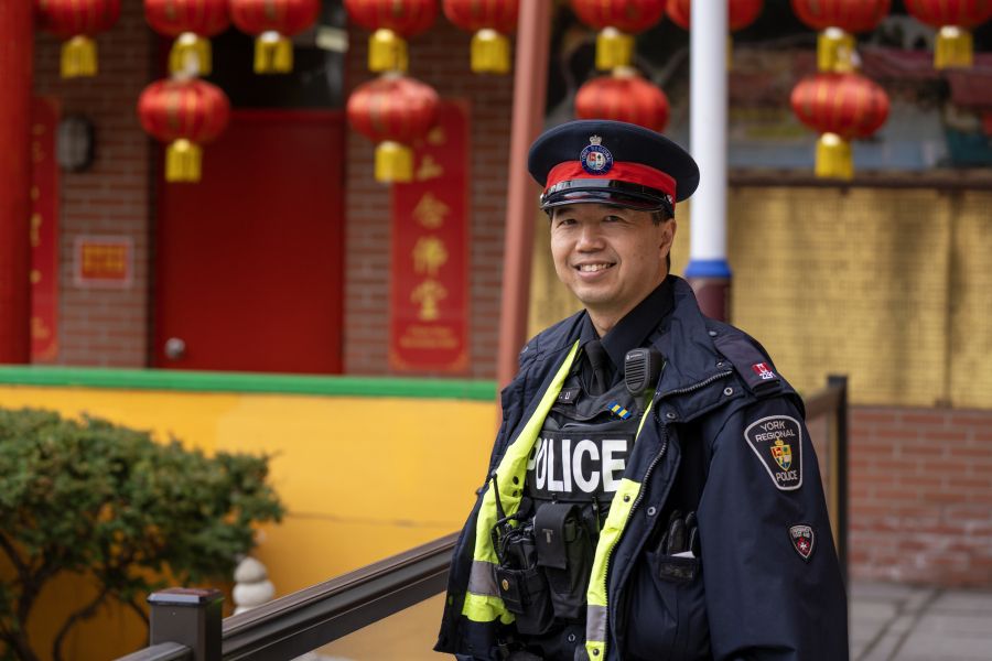 A man in a uniform smiles in front of lanterns