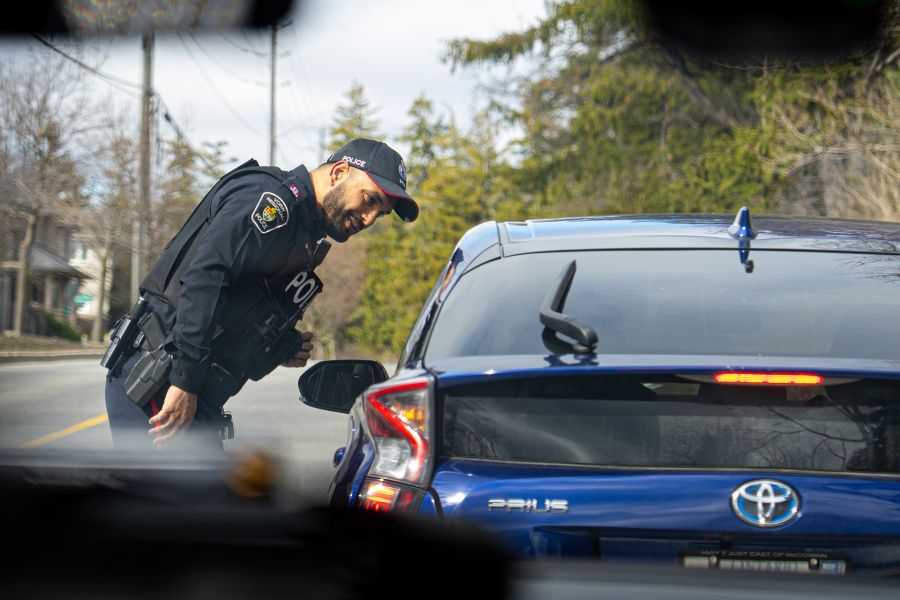 An officer leans in to speak to the driver of a blue vehicle