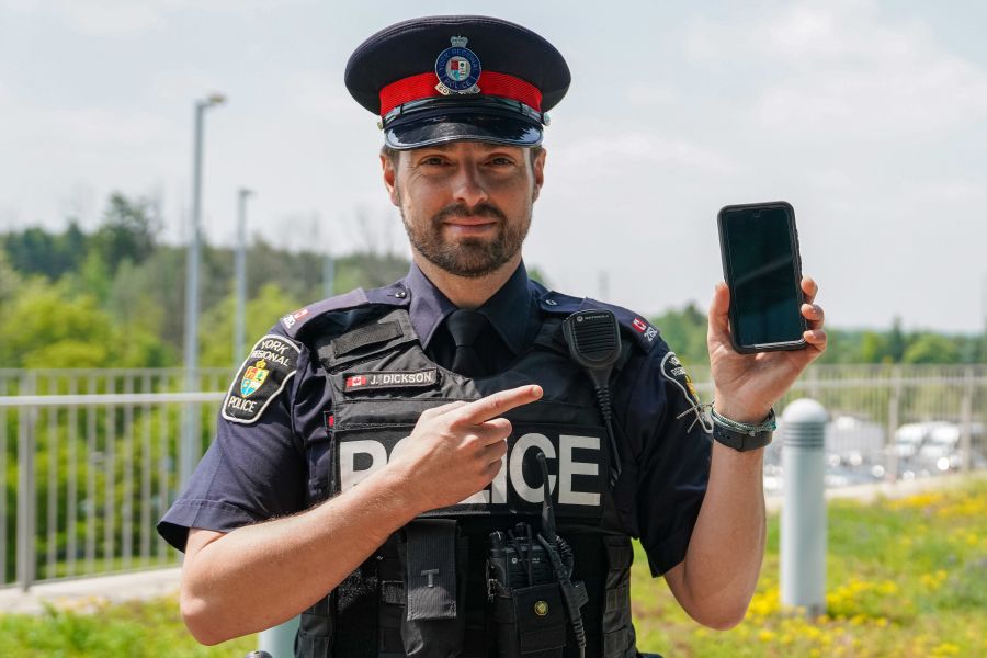 A man in a police uniform holds a phone