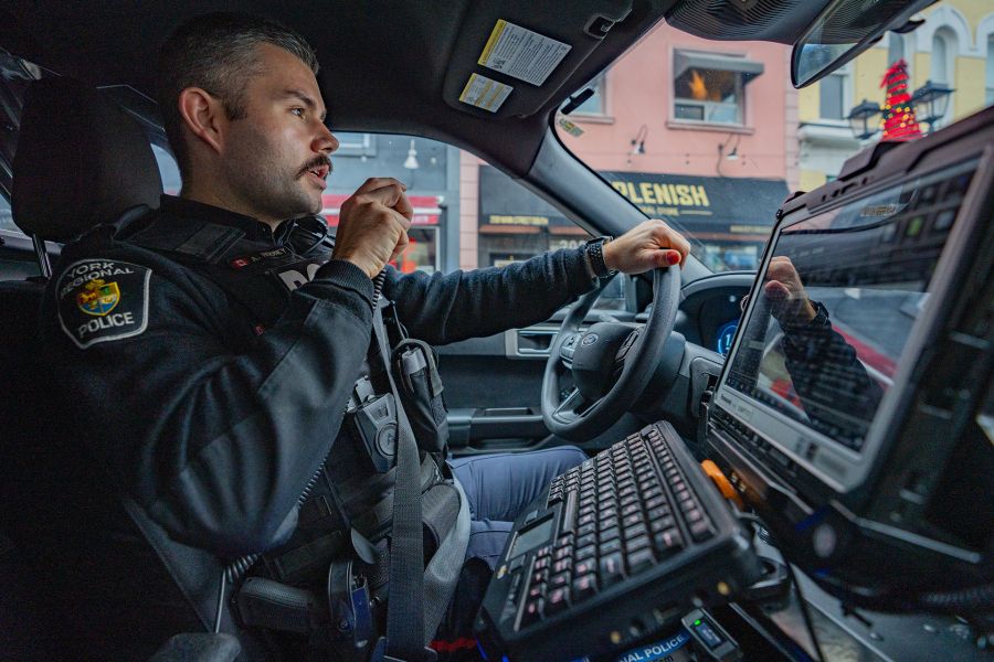 An officer speaks on his radio in a cruiser