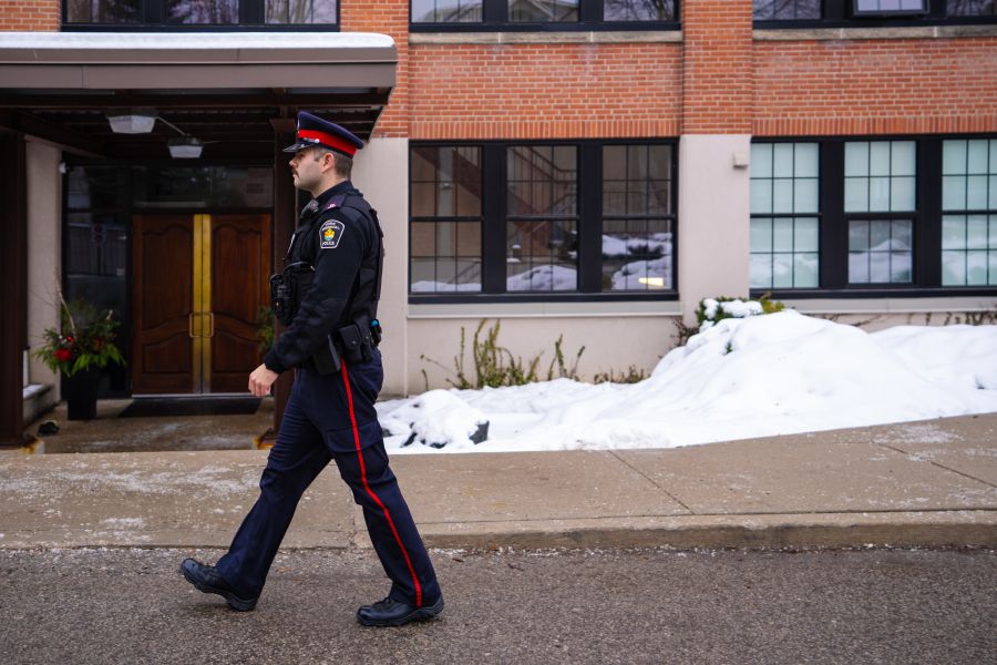 Police officer walking in front of building with windows.