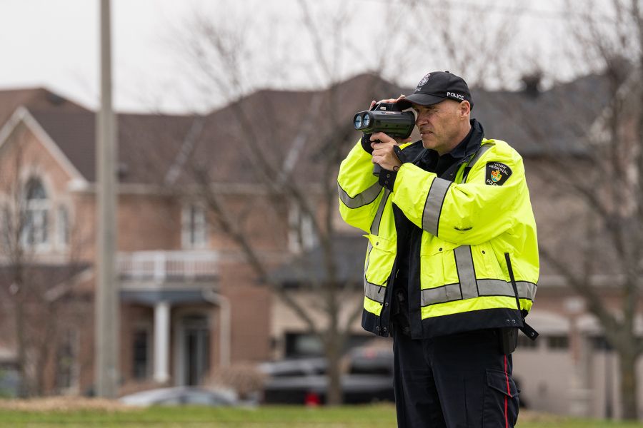An officer conducts radar speed enforcement in a neighbourhood