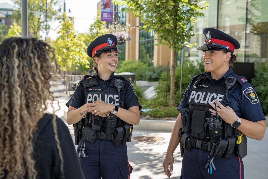 Two police officers laughing with civilian at a park.