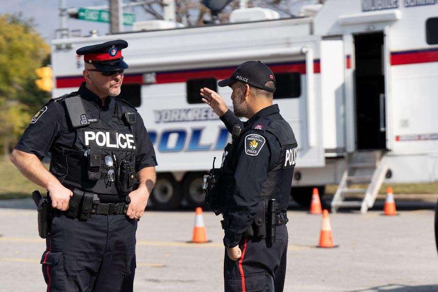 Two officers speak in front of the mobile command centre.