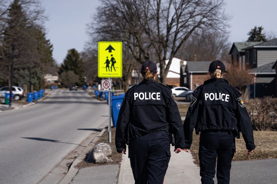 Two officers walk past a school crossing sign.