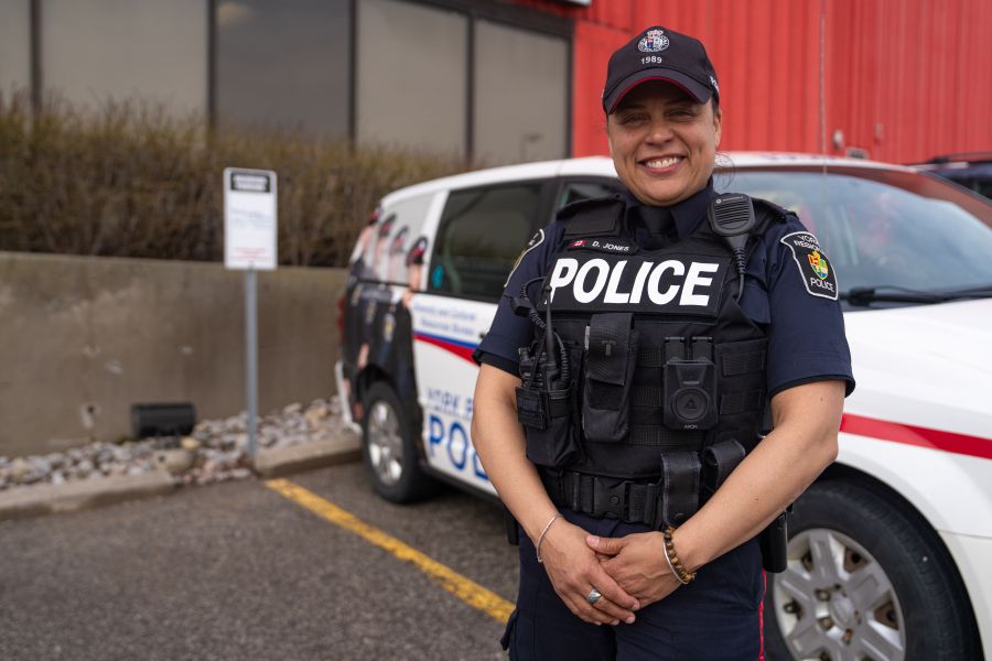 An officer smiling in front of a cruiser with decals about diversity.