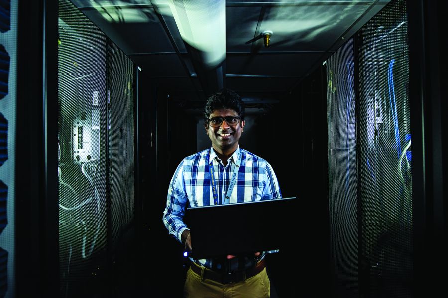 A man holds a laptop in a dark room