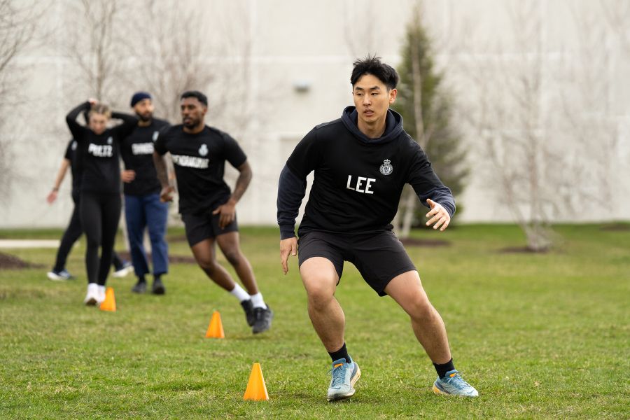 Police recruit running on a grassy field in gym clothes.