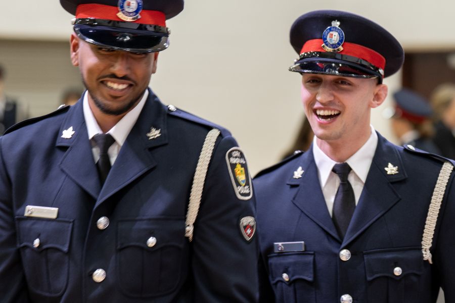 Two men in formal uniforms smile
