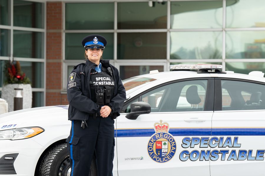 A woman smiles next to a car that reads SPECIAL CONSTABLE