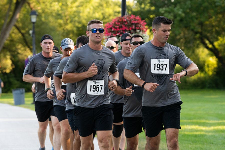 A group of men in matching gym clothes run in two lines on an outdoor path.
