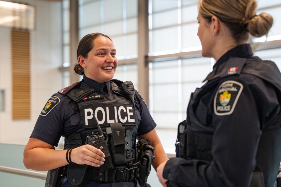Two women in uniform smile and talk