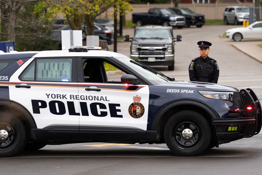A man in a uniform stands next to a police vehicle