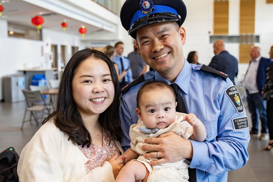 Two parents hold their child, one wears a uniform