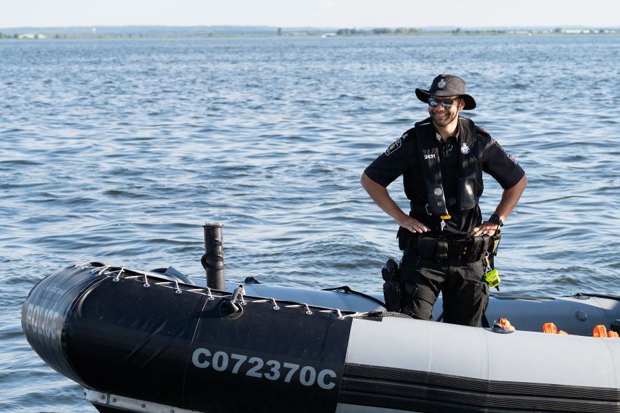 A man in a tilley hat stands on a small boat