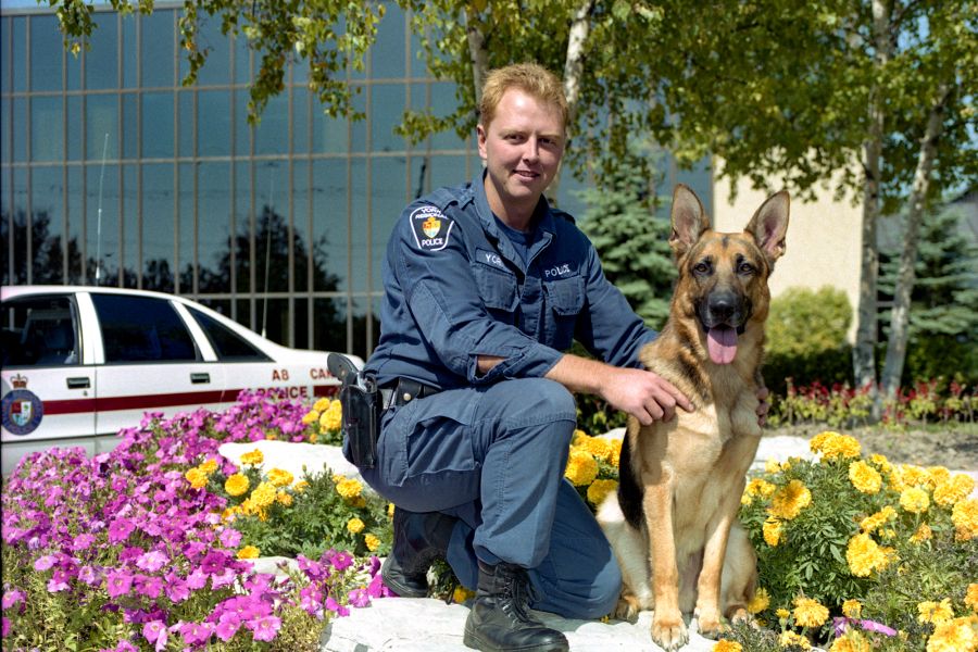 A man and a dog next to a police cruiser