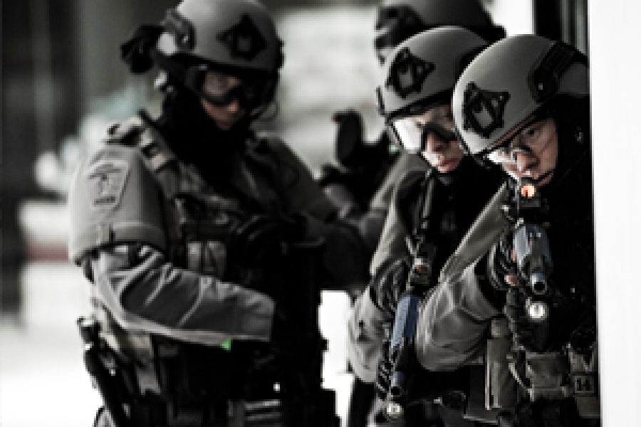 A group of officers wearing grey equipment readies their guns