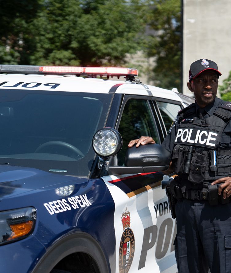 A man in a police uniform next to a police cruiser